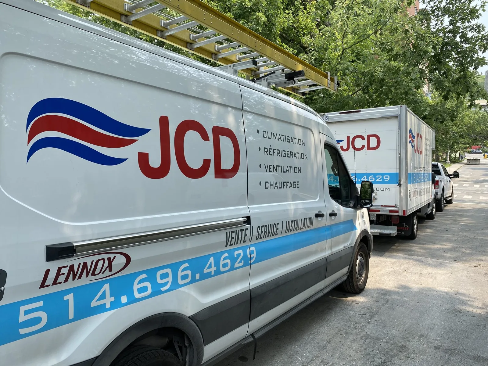 Une fourgonnette de service et un camion cube JCD stationnés dans une rue