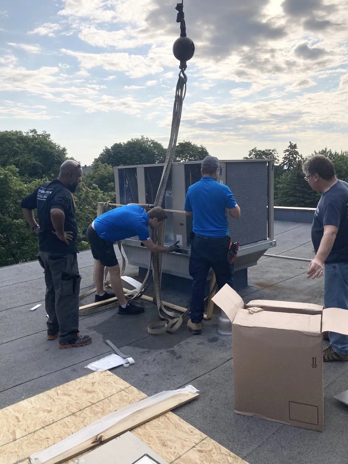 A JCD crew guiding a replacement rooftop unit lifted by crane