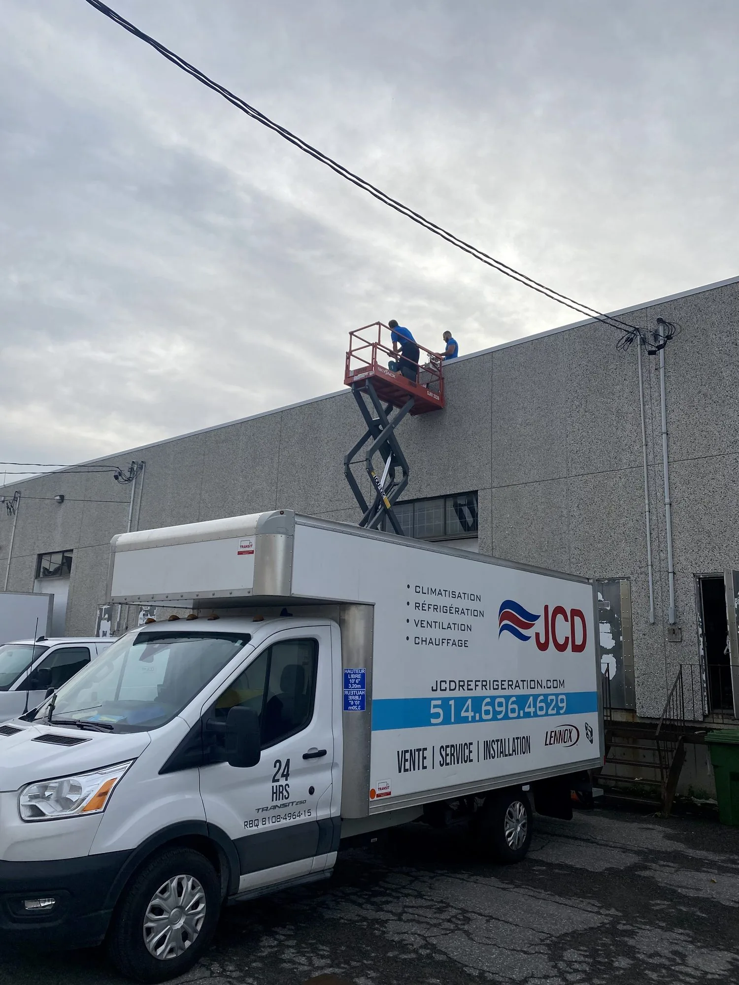 A JCD box truck and a scissor lift at a commercial building