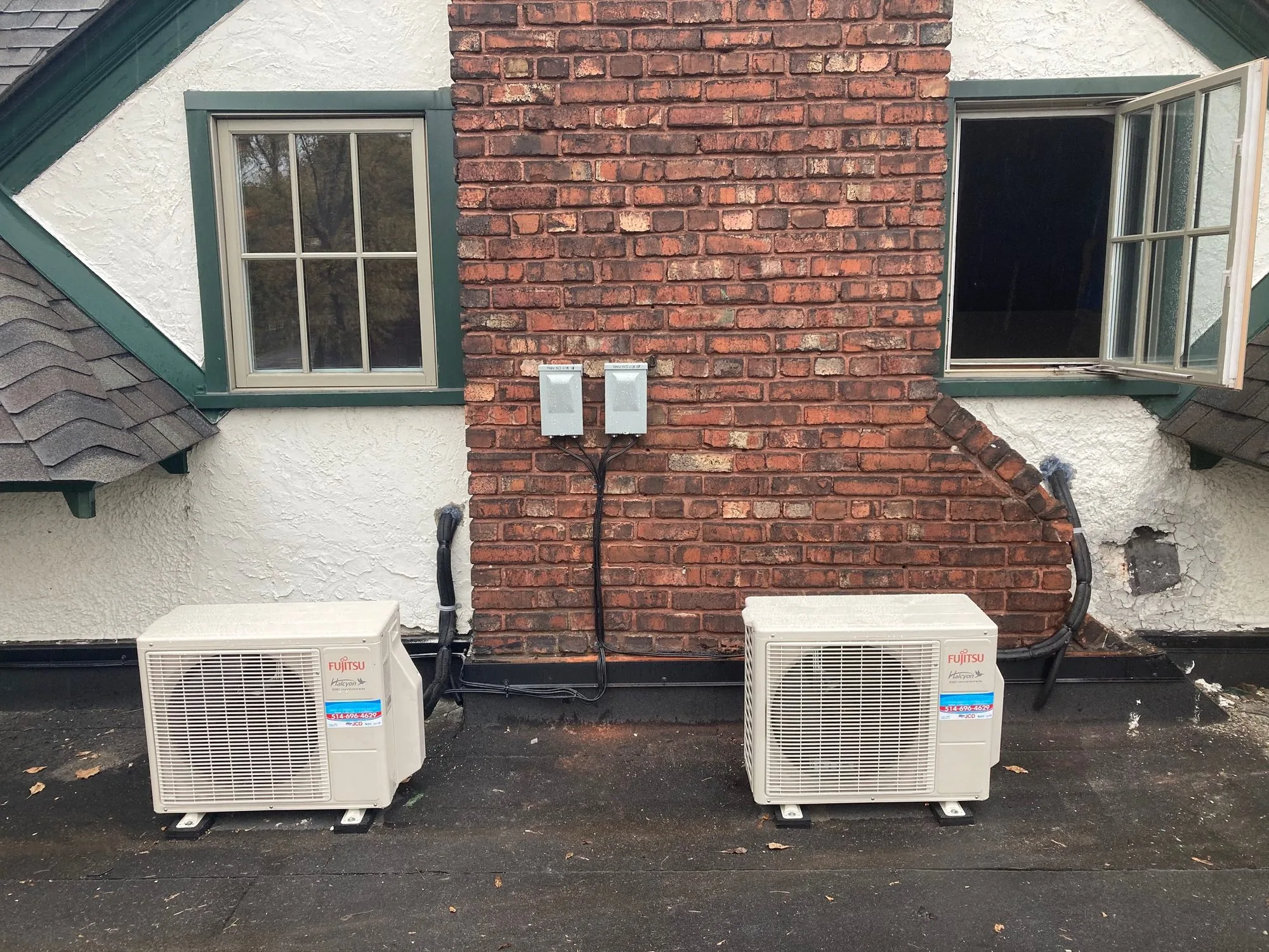 Two ductless heat pump outdoor units against the wall of a house