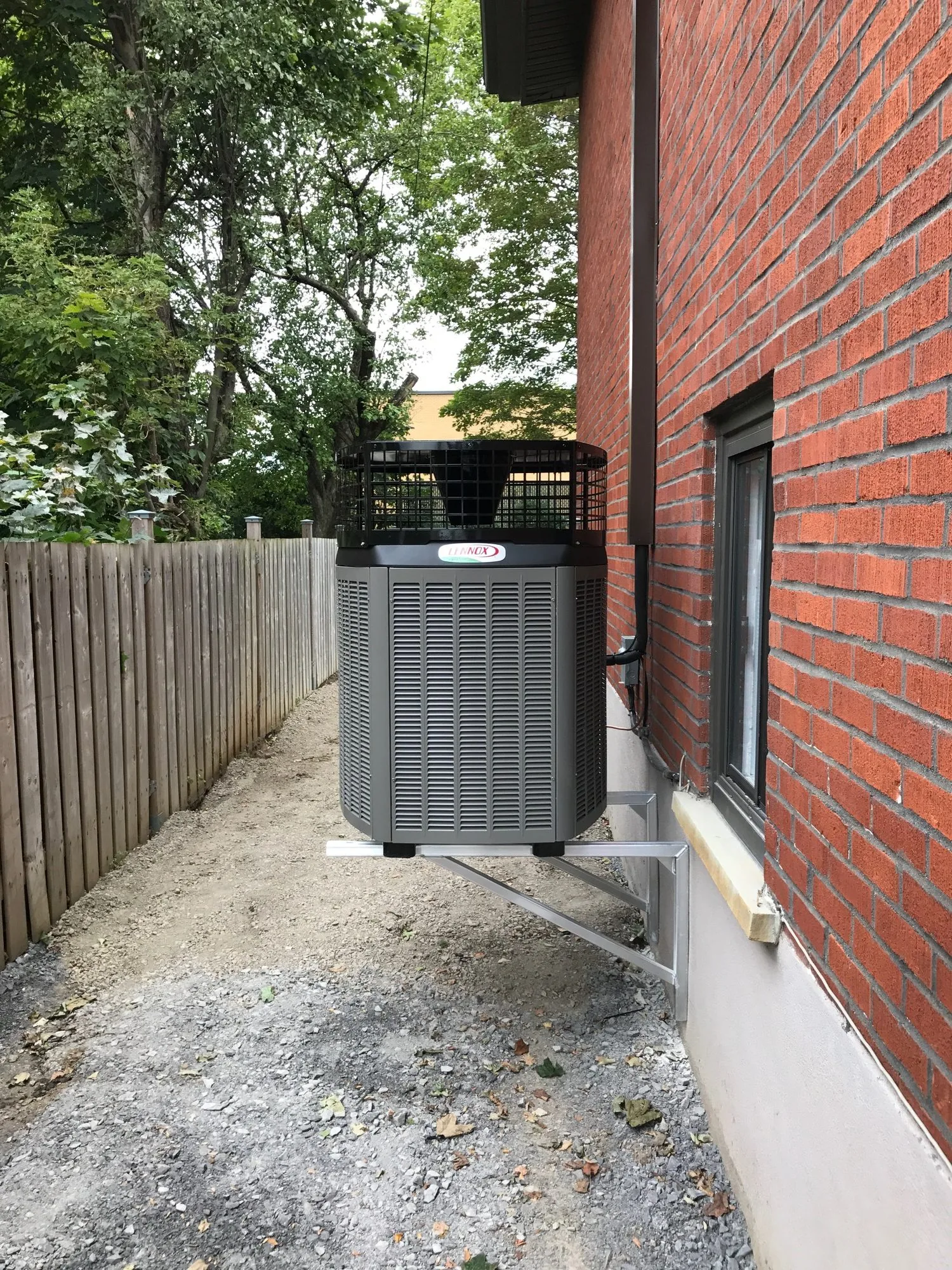Appareil extérieur Lennox sur un support mural, à côté d’une maison